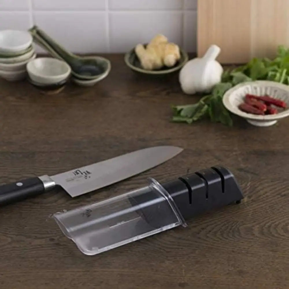 Knife sharpener on a wooden surface with a kitchen setting in the background