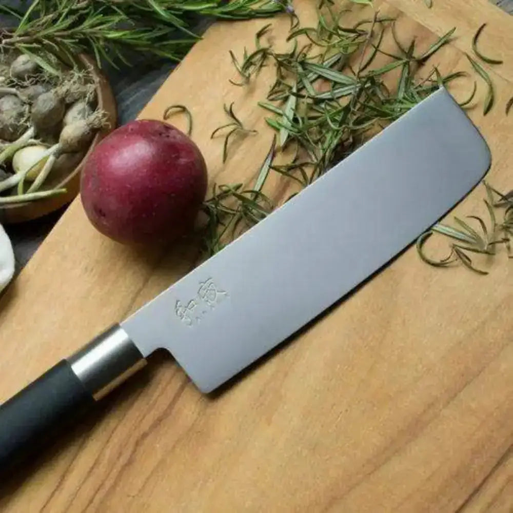 Knife on a wooden cutting board with herbs and an onion
