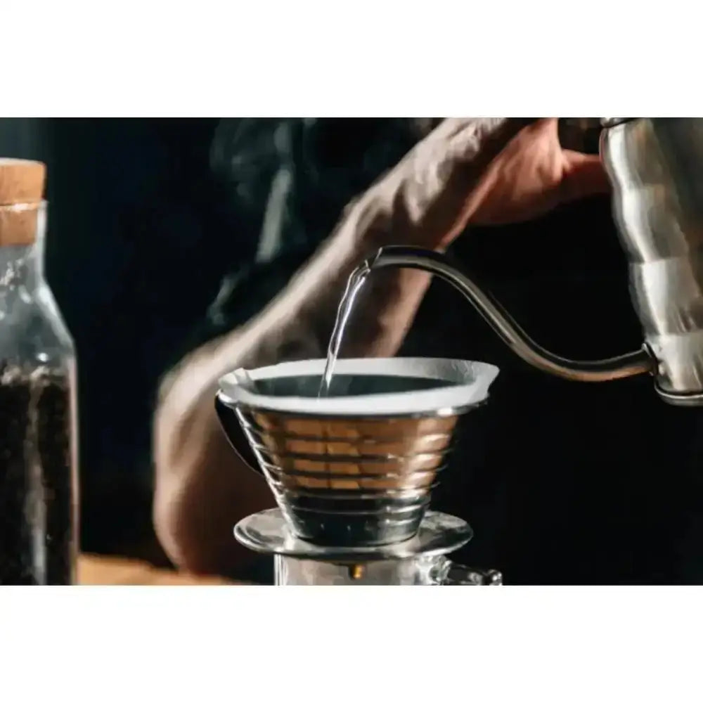 Person pouring liquid into a coffee filter with a dark background
