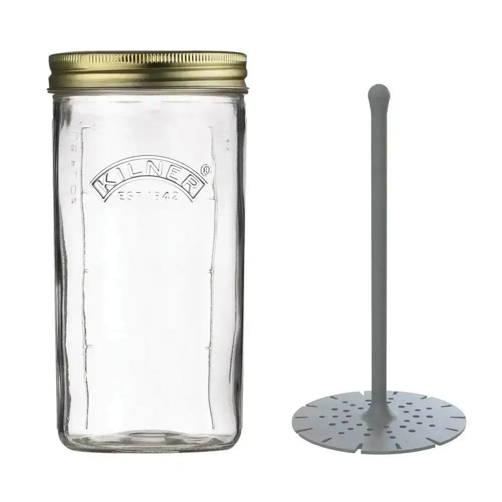 Clear glass jar with gold lid and metal strainer on a white background