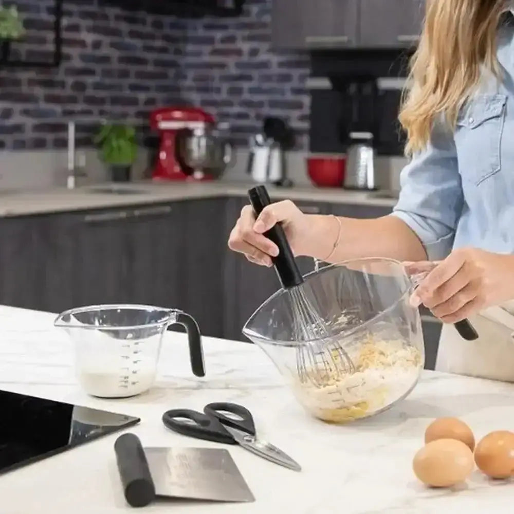 Person mixing ingredients in a kitchen with various utensils and appliances.