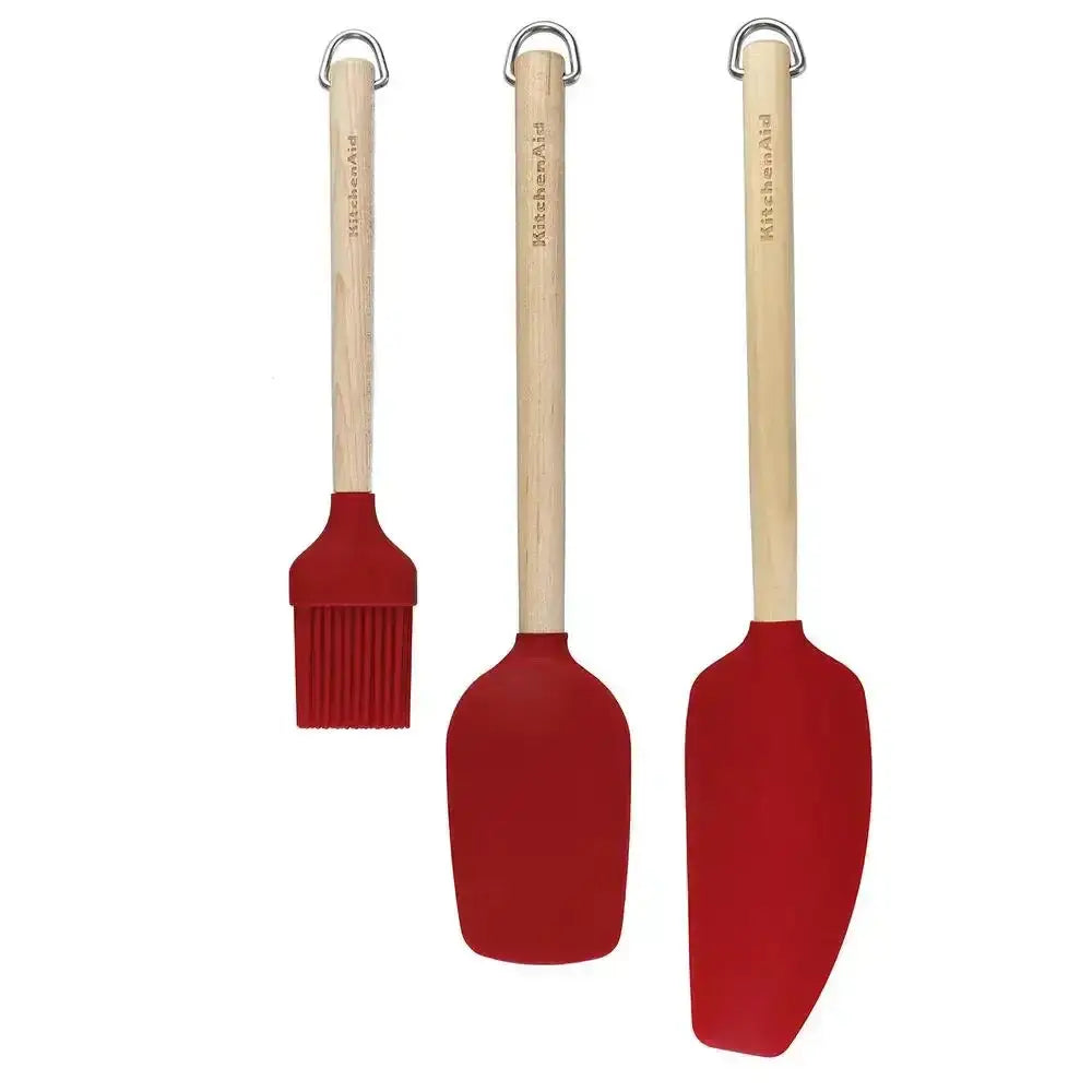 Three red silicone kitchen utensils with wooden handles on a white background