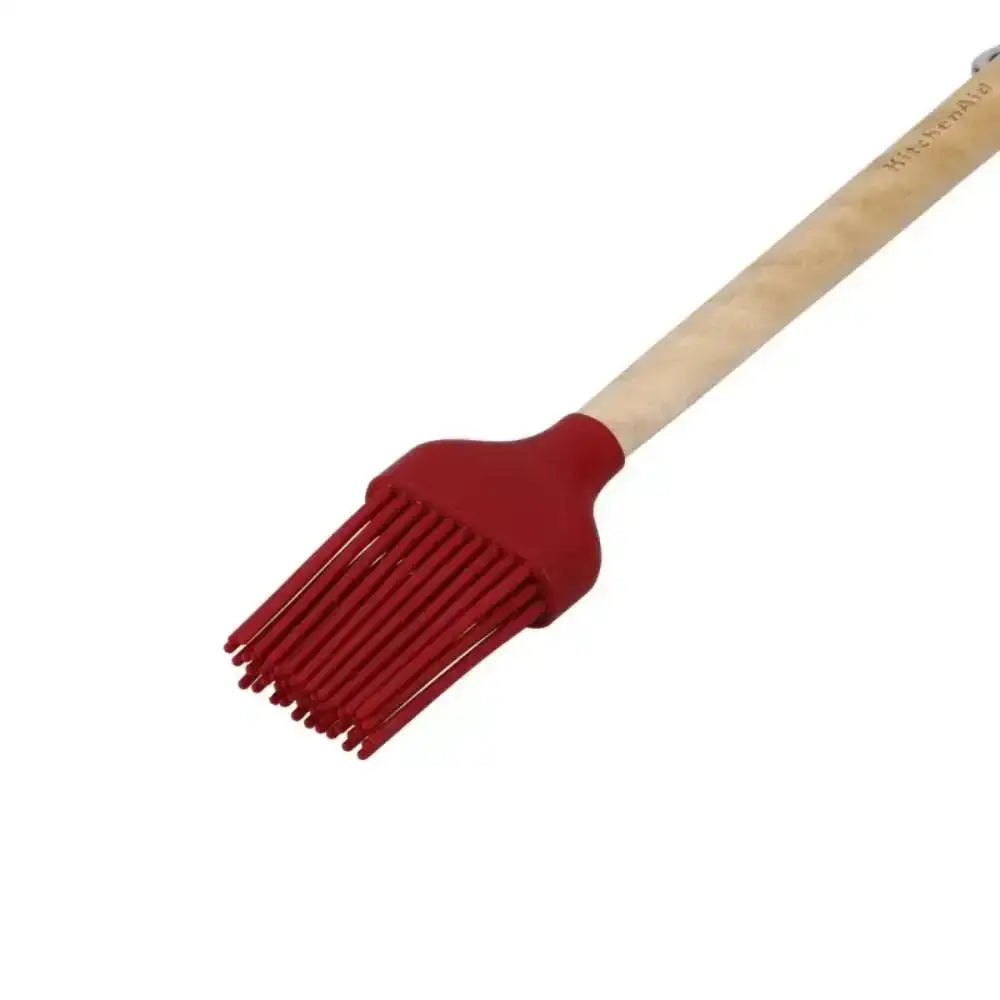 Red silicone brush with wooden handle on a white background
