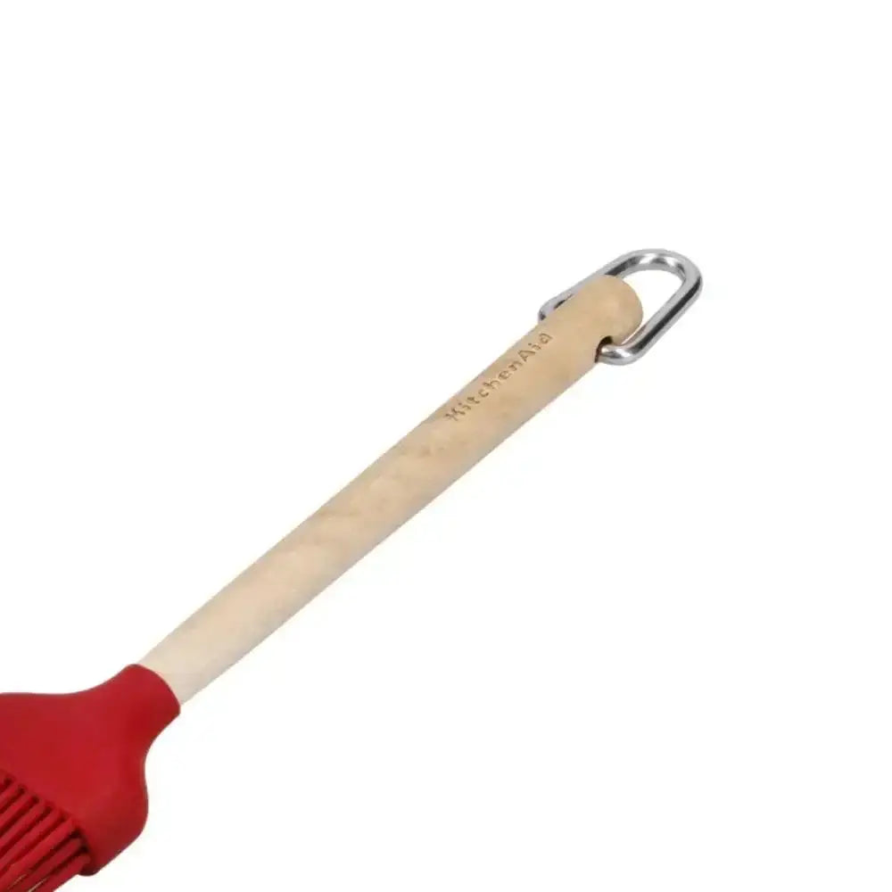 Red silicone brush with a wooden handle on a white background