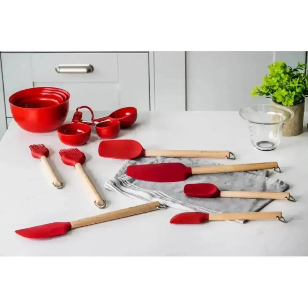 Red kitchen utensils including spatulas and measuring cups on a white surface.