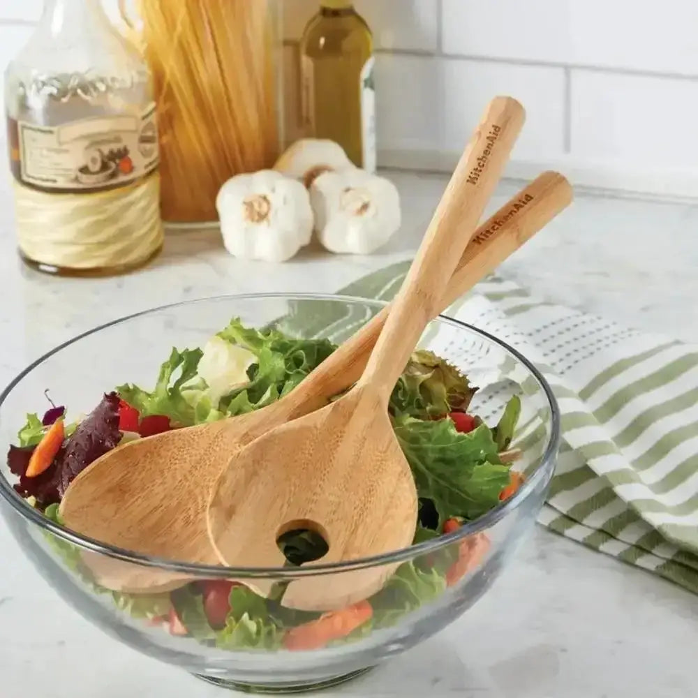 Glass bowl with salad and wooden spoons on a kitchen counter