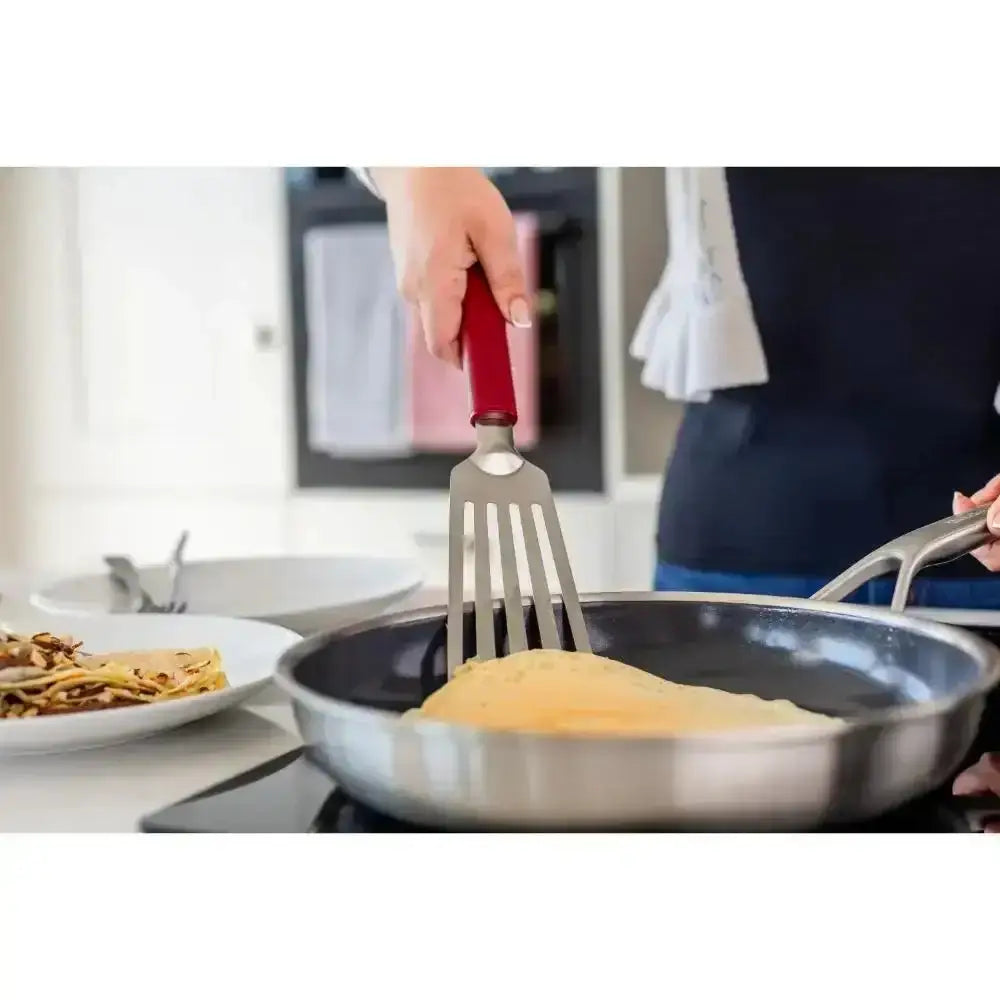 Person cooking scrambled eggs in a pan with a spatula, kitchen setting.
