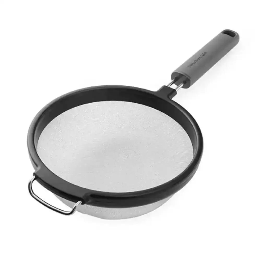 Black frying pan with a mesh strainer on a white background