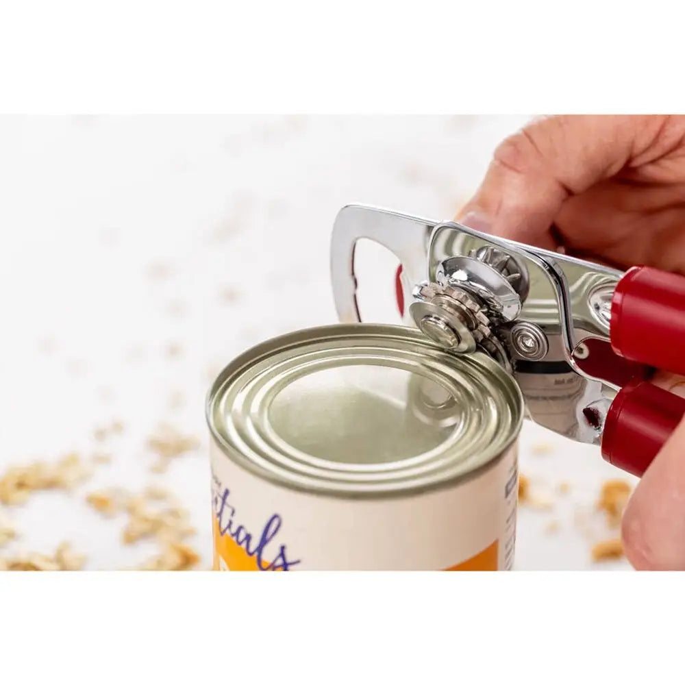 Stainless Steel Can opener with red finish openinh a can on a blureed background