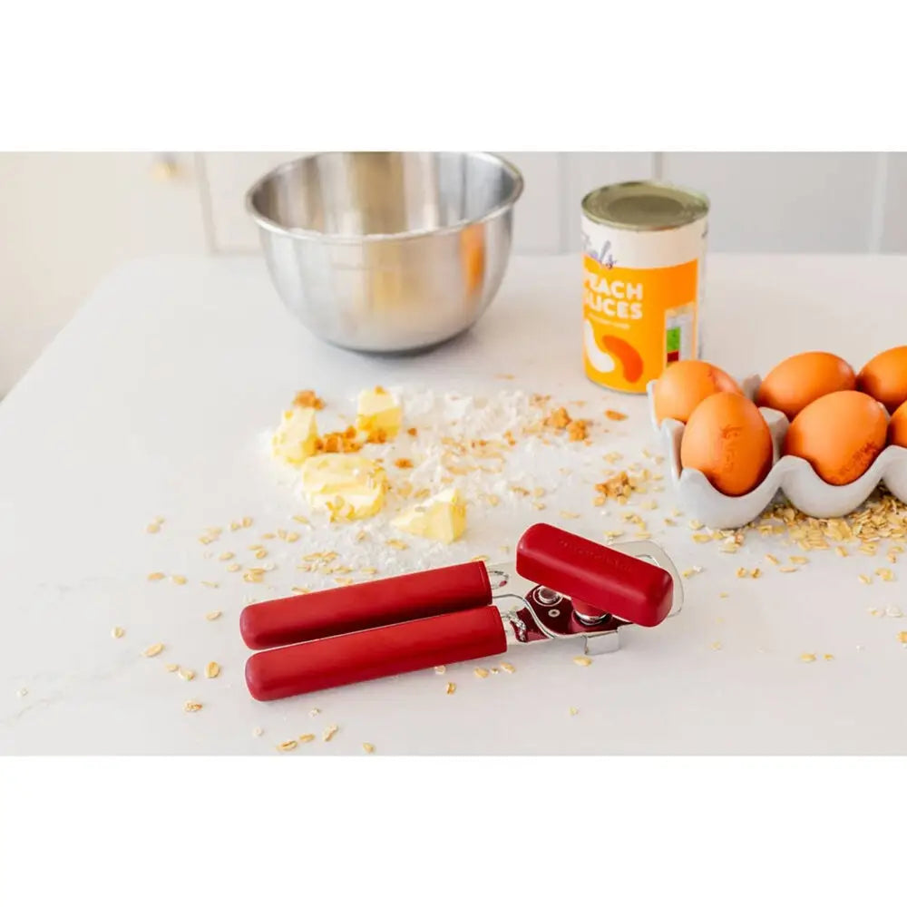 Stainless Steel Can opener with red finish with kitchen stuff in the background