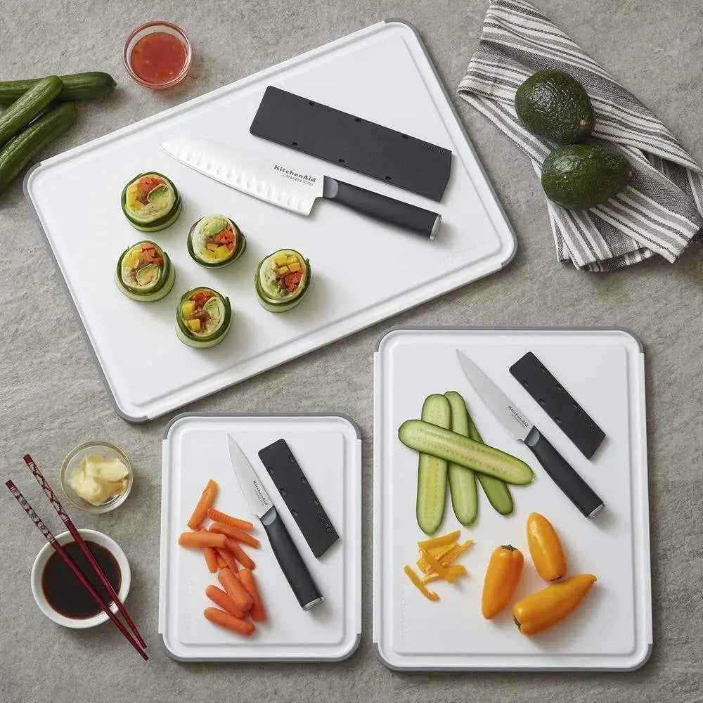 Set of cutting boards with vegetables and knives on a gray surface