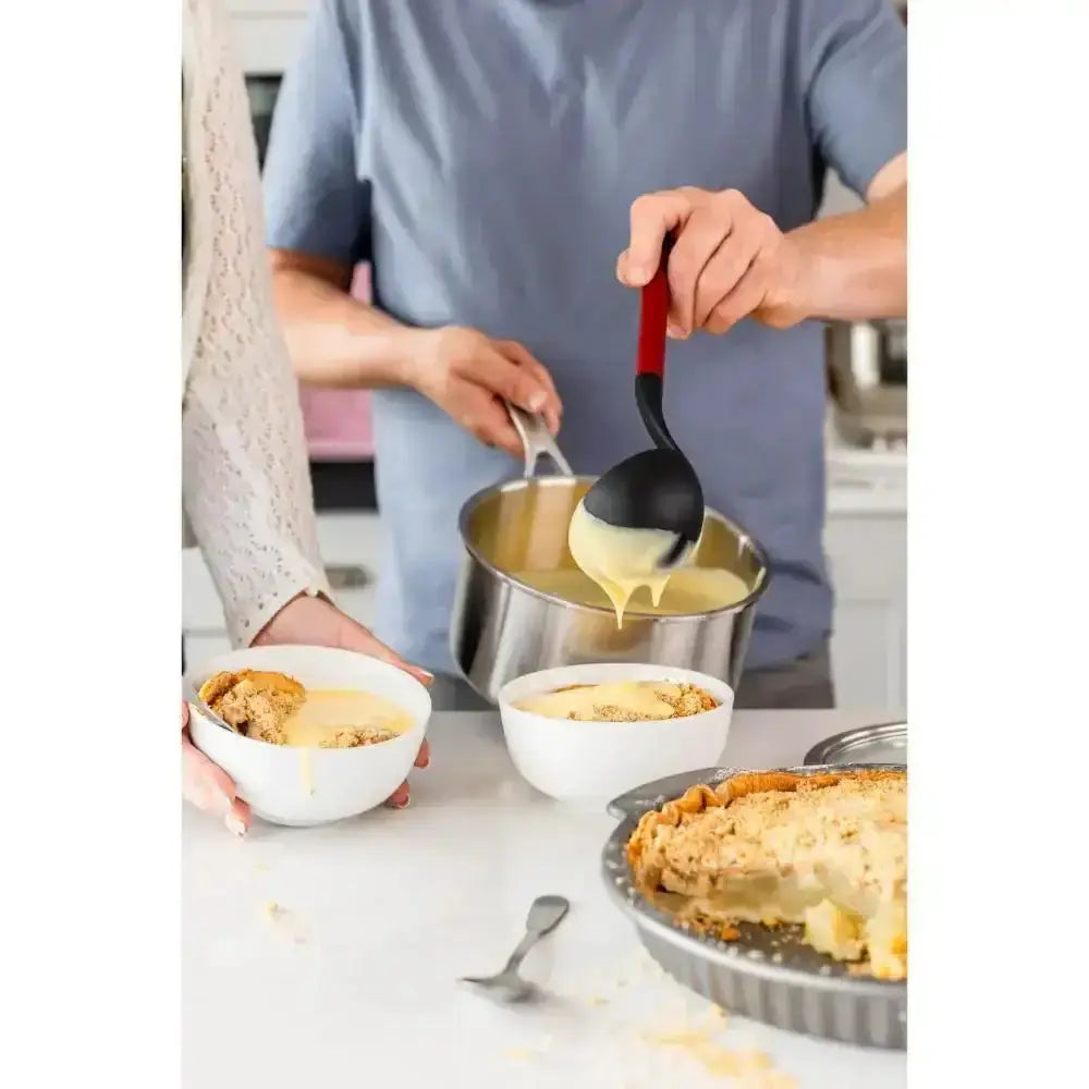 Person serving dessert from a pie into bowls with a ladle.