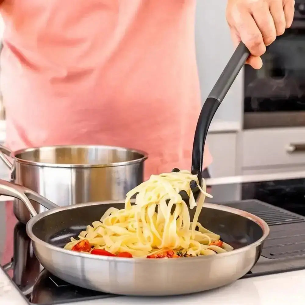 Person cooking pasta in a pan with a kitchen background