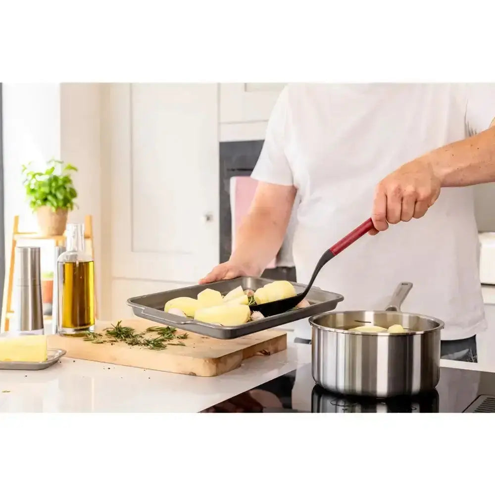 Person cooking potatoes in a kitchen setting with various kitchen items.