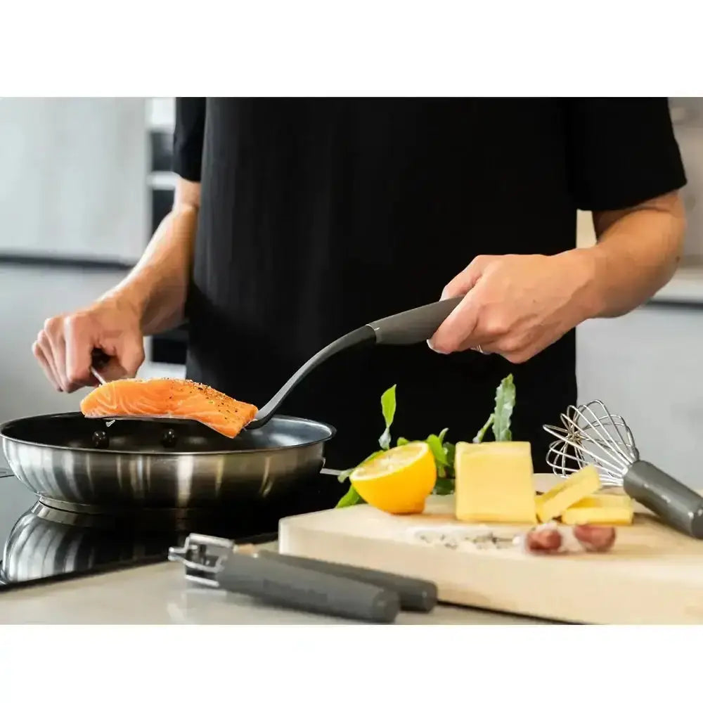 KitchenAid classic nylon slotted turner grey lifting seasoned salmon fillet with black handle from stainless steel pan