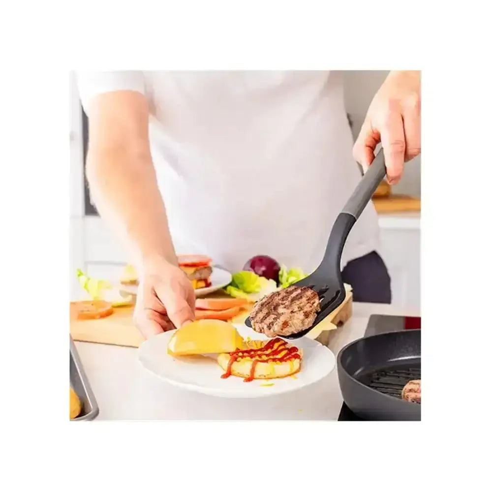 Black kitchenAid classic nylon slotted turner with long ergonomic handle lifting a cooked burger patty