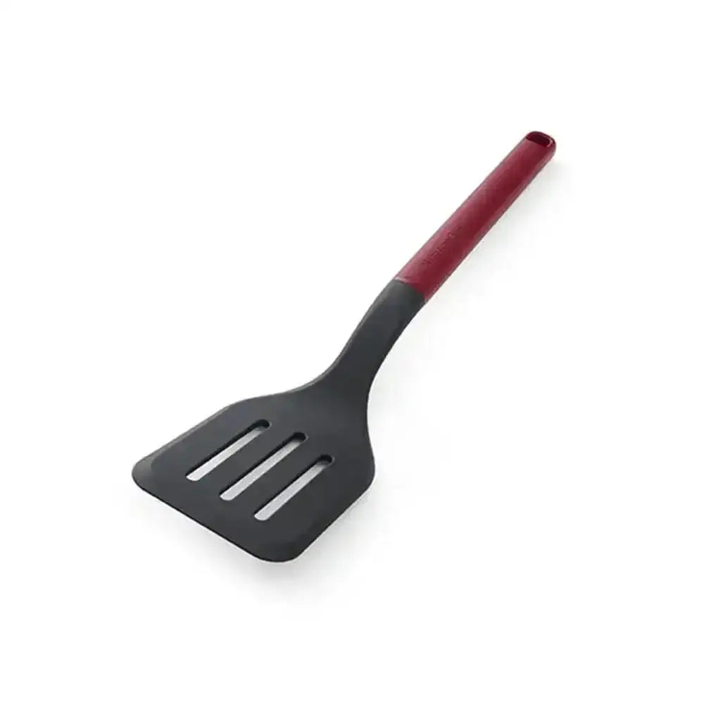 Black slotted spatula with red handle on a white background