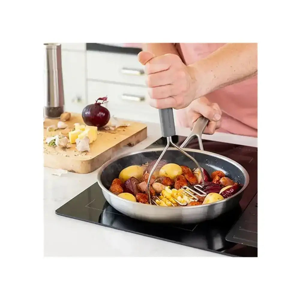 Person using tongs to stir food in a frying pan on a stove