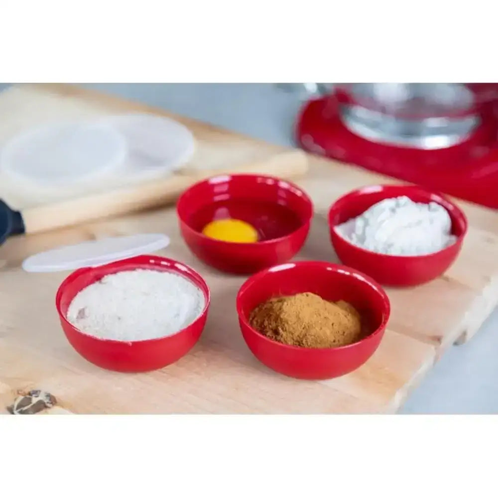 Four red bowls with different ingredients on a wooden surface