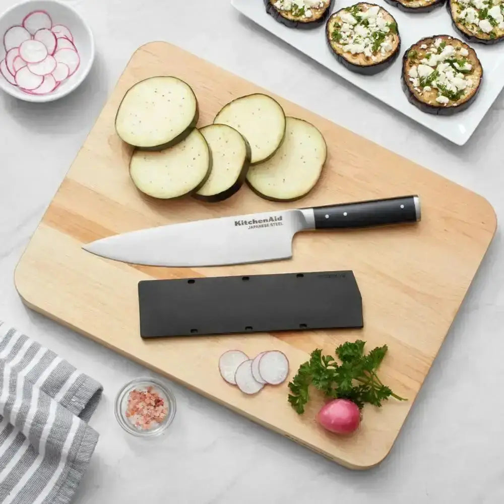 Wooden cutting board with sliced zucchini, a knife, and a sharpener on a light gray surface.