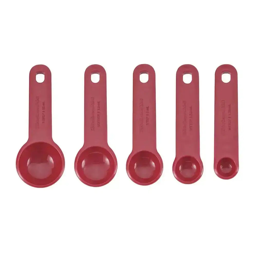 Set of five red measuring spoons on a white background