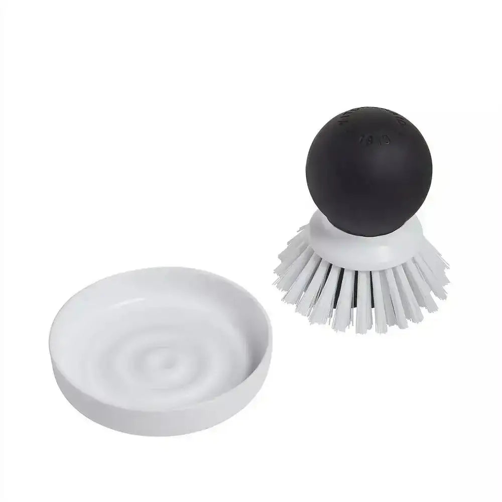 White dish scrubber with black handle on a white background