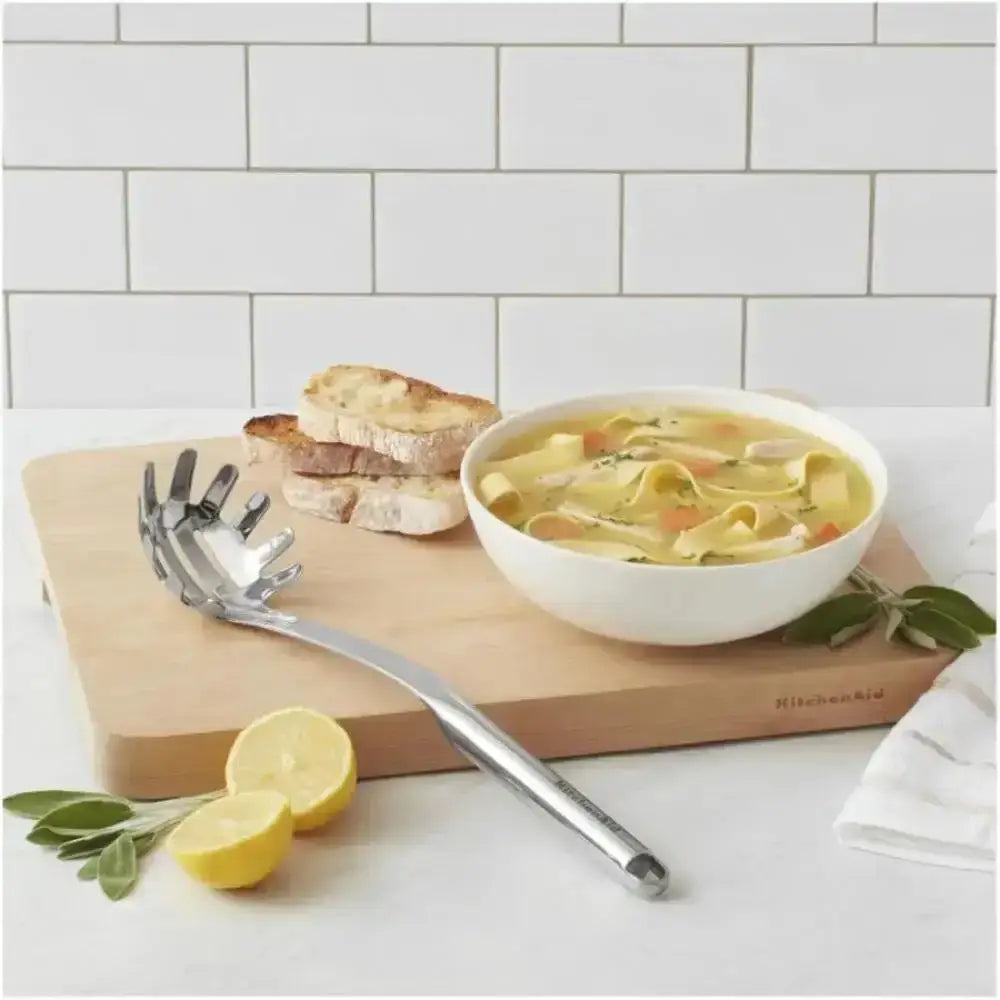 Bowl of soup on a wooden cutting board with bread and lemons, featuring a KitchenAid product.