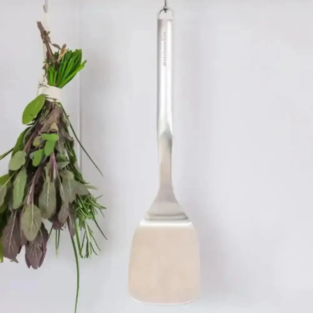 White spatula with a bundle of herbs hanging on a white background