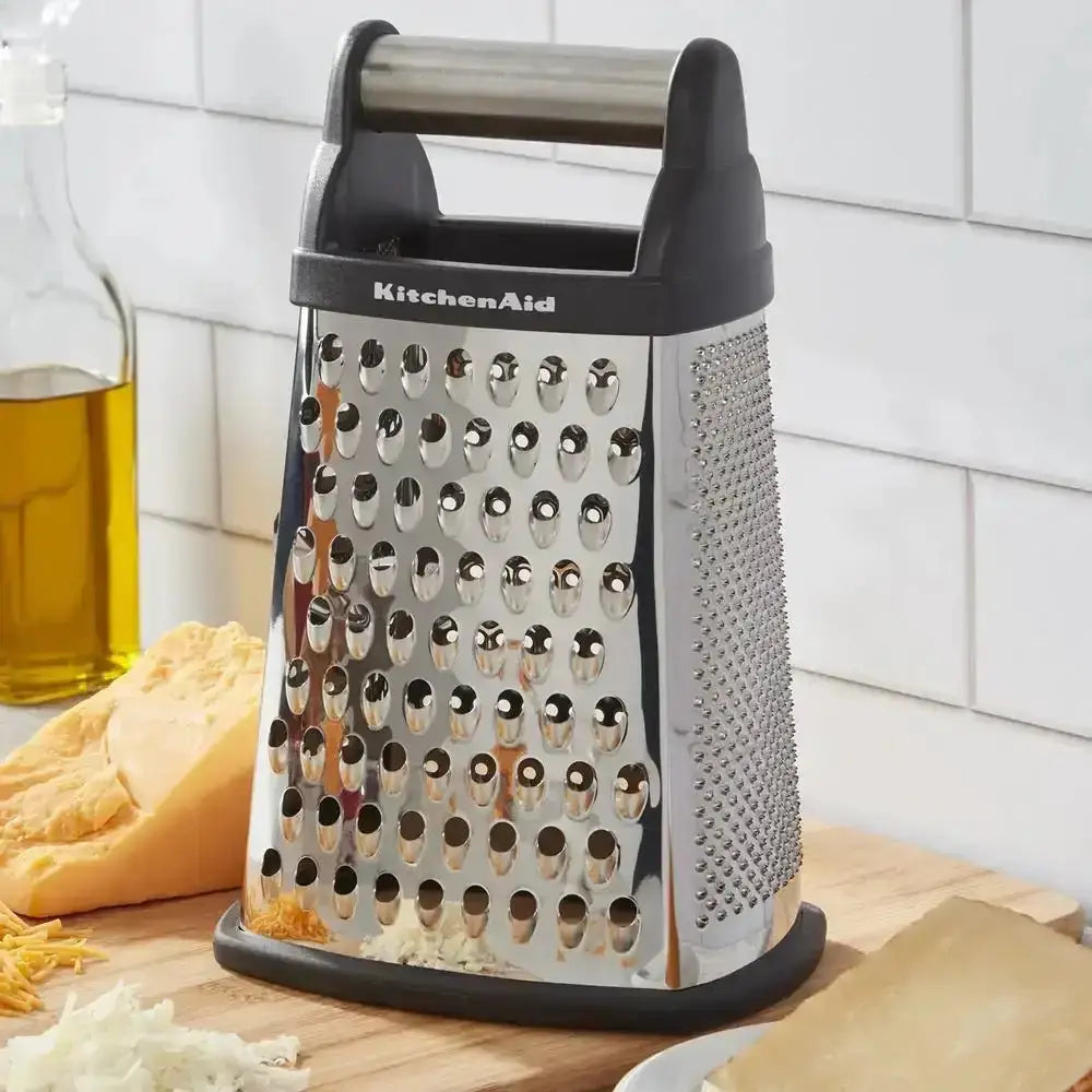 KitchenAid box grater on a kitchen counter with cheese and oil in the background