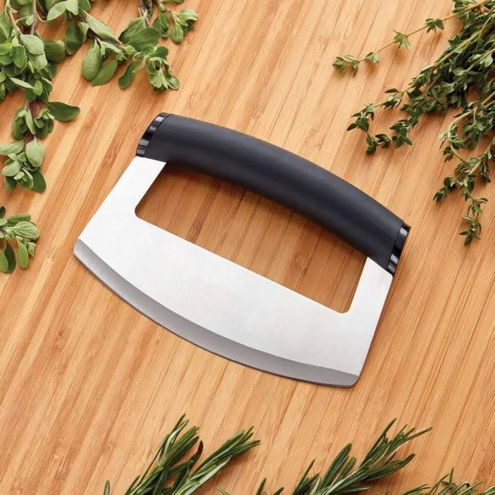 Mezzaluna knife with black handle on a wooden surface with herbs