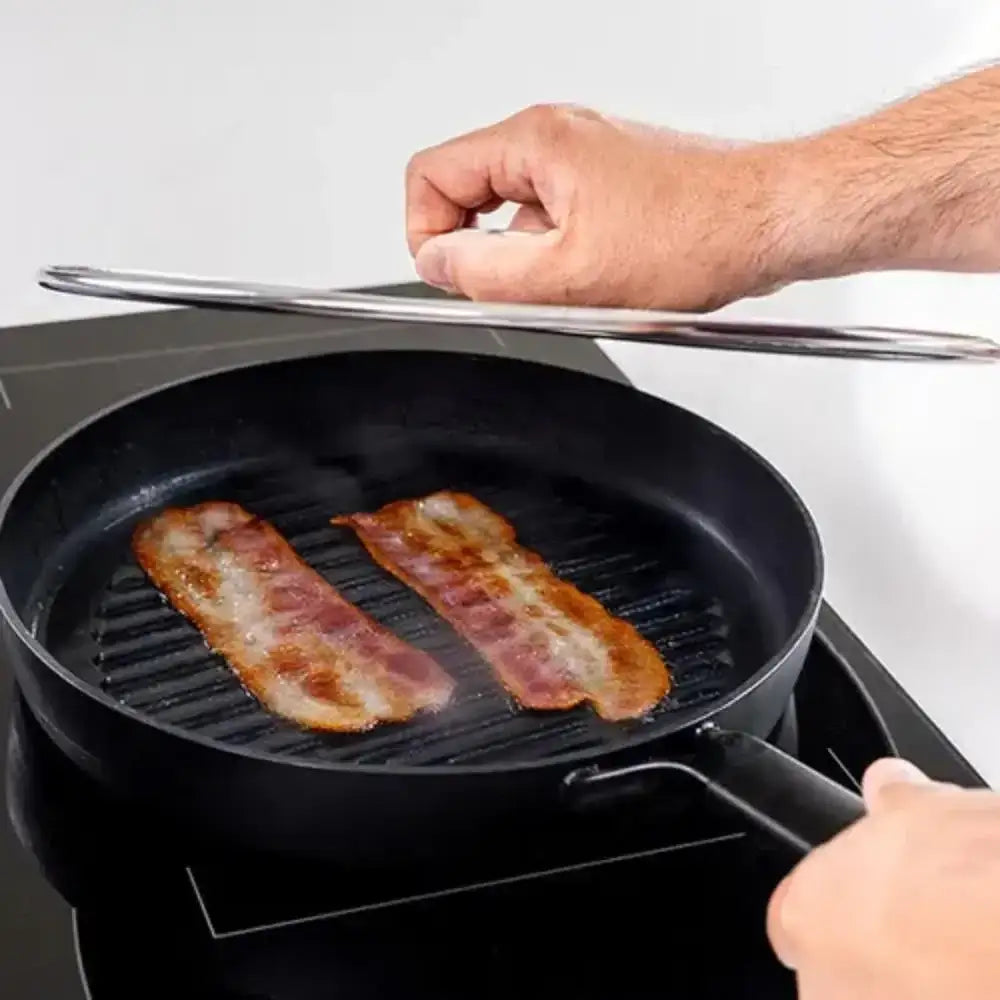Person cooking bacon in a black grill pan on a stove.