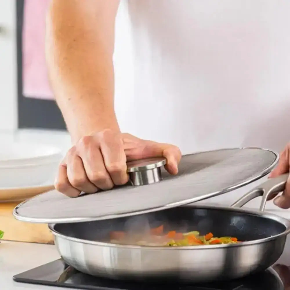 Person using a lid on a frying pan with vegetables cooking inside