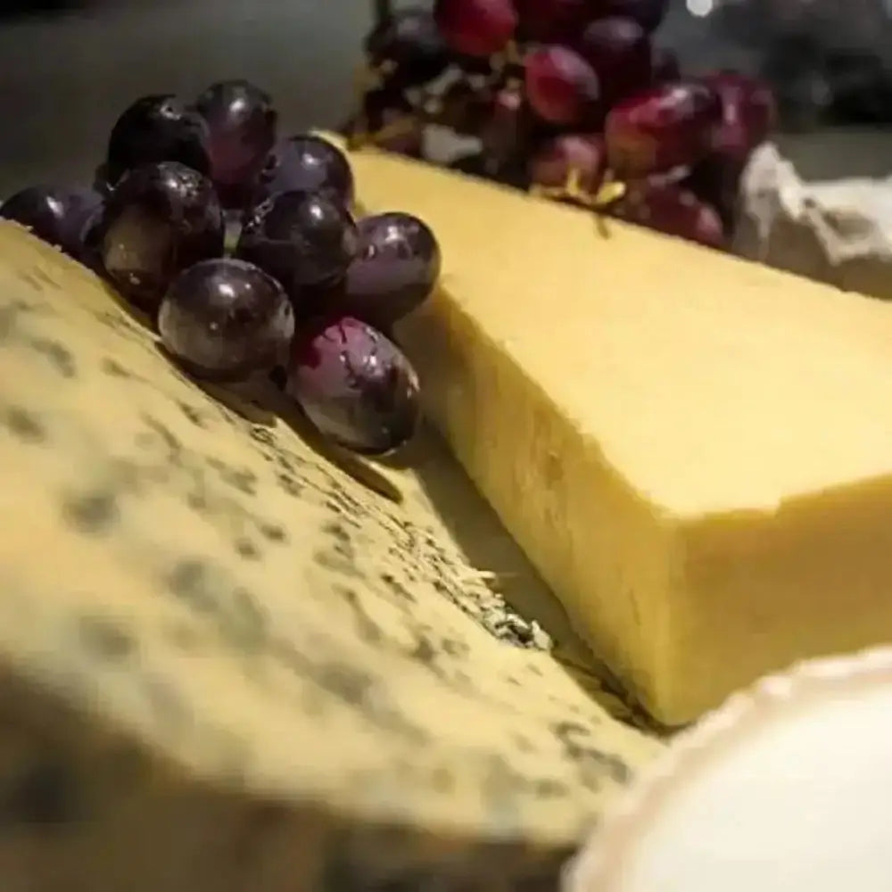 Close-up of a block of cheese with purple grapes on top