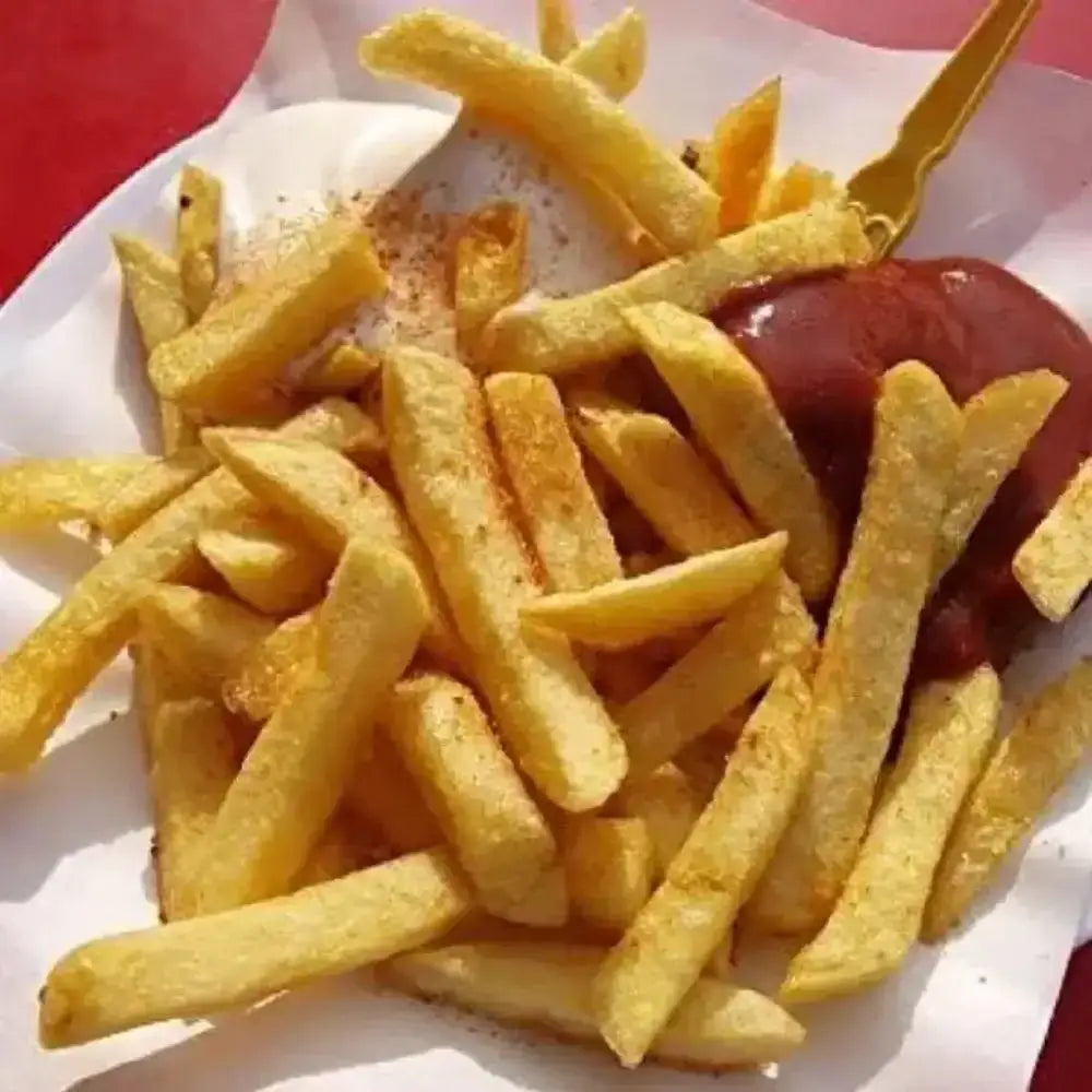 Fries with a side of ketchup on a white paper plate against a red background