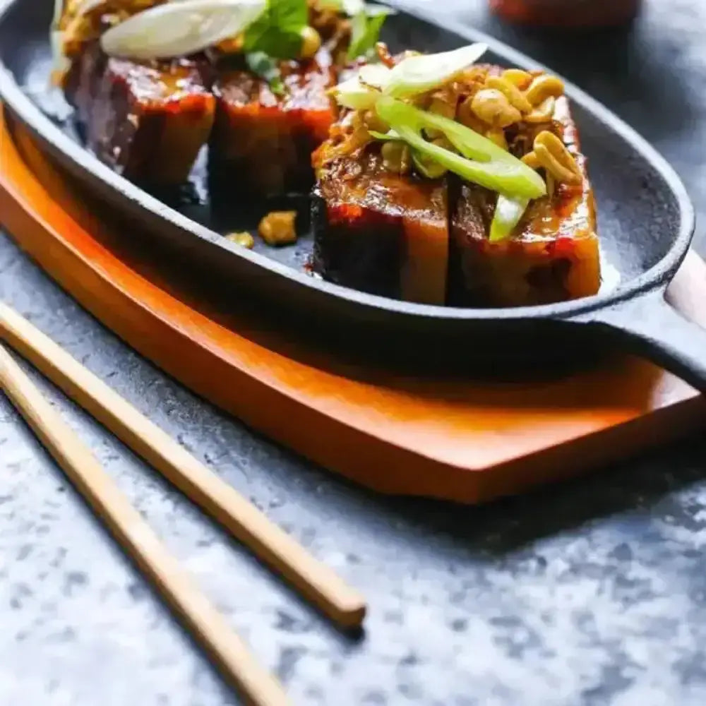 Dish of food on a boat-shaped plate with chopsticks on a gray surface