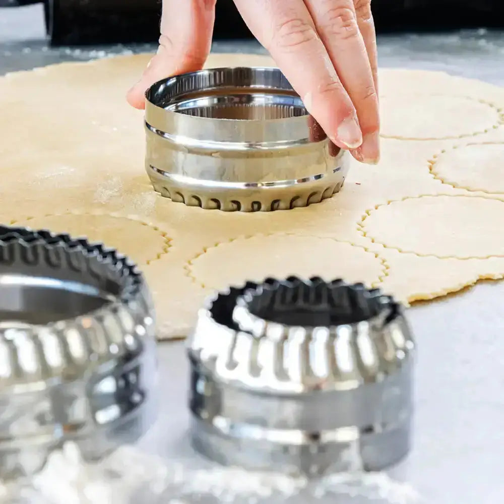 Metallic pie crust cutters being used on rolled-out dough