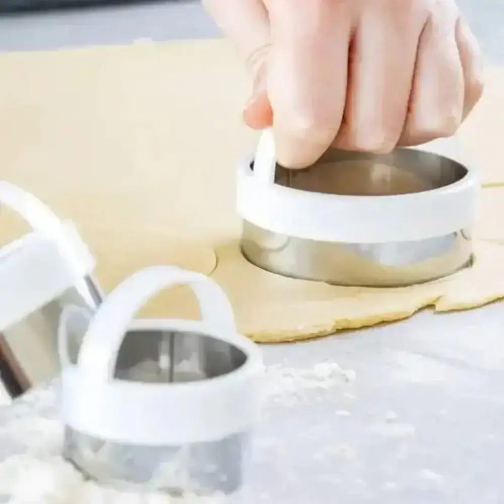 Person using a metal cookie cutter on rolled-out dough