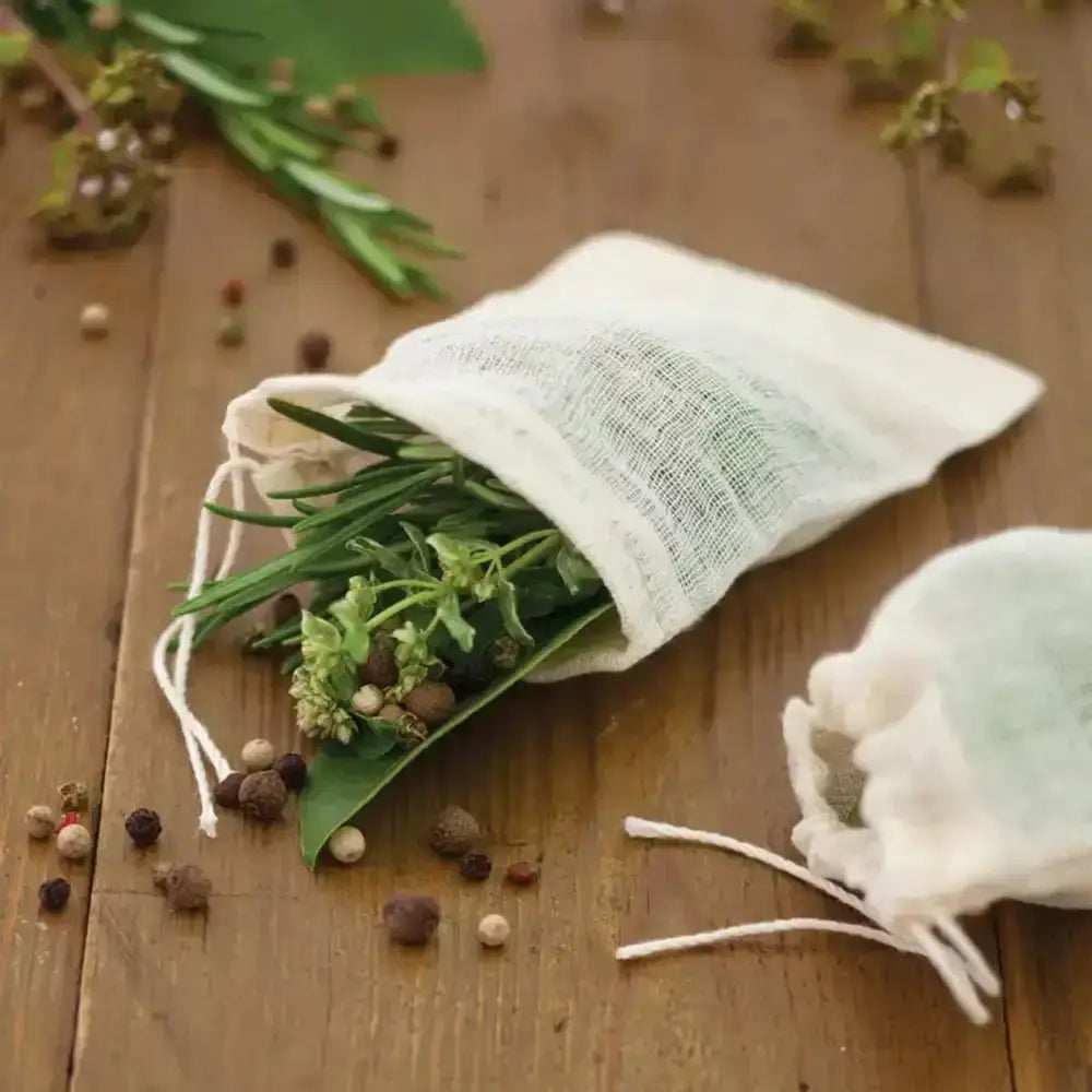 Herbal bags with green leaves and peppercorns on a wooden surface