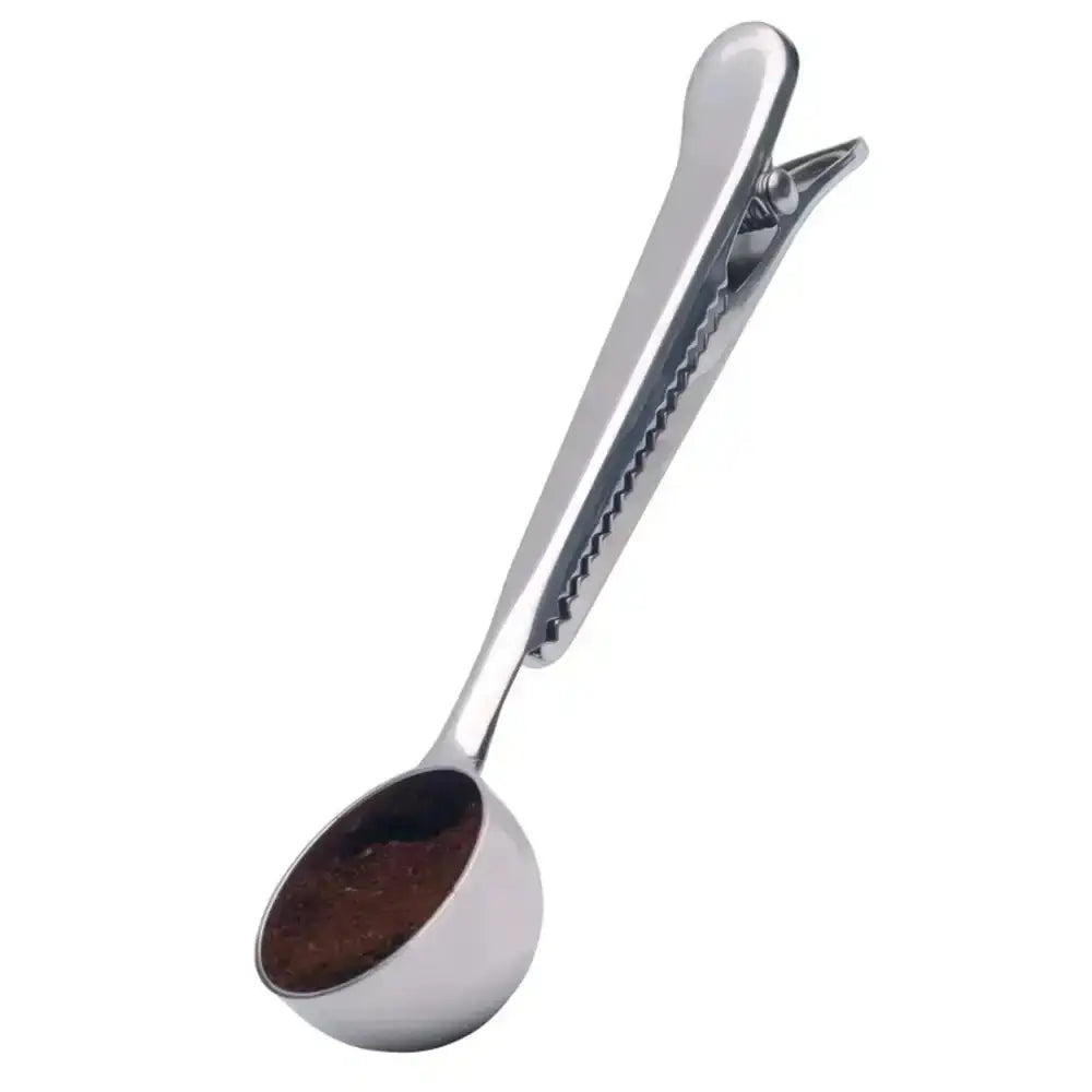 Metallic coffee scoop with a small amount of ground coffee on a white background