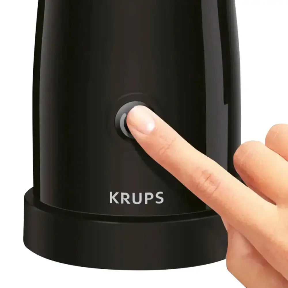 Black KRUPS milk frother with a hand pressing the button on a white background
