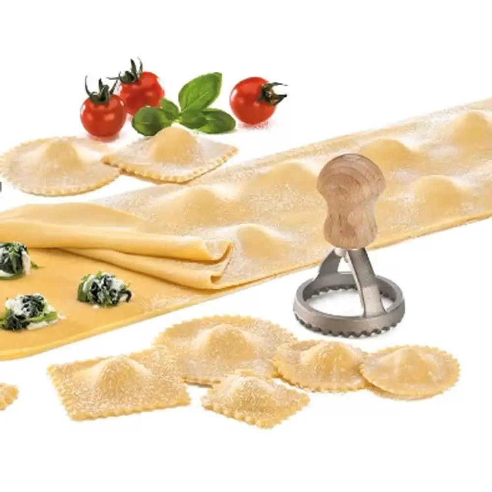 Pasta making tool with ravioli and fresh ingredients on a white background