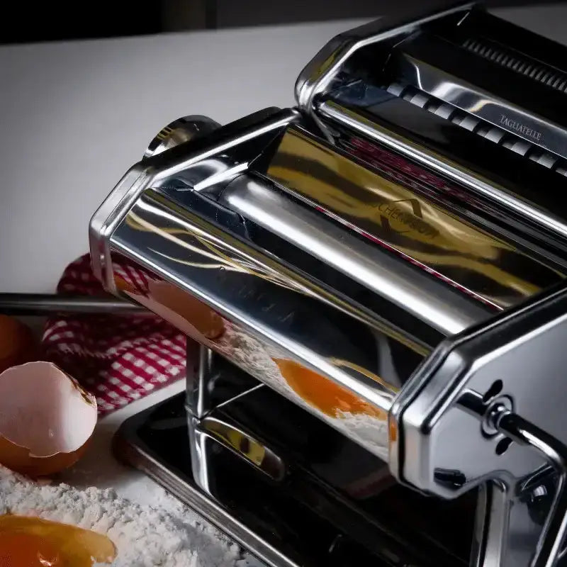 Pasta maker on a table with flour and eggshells