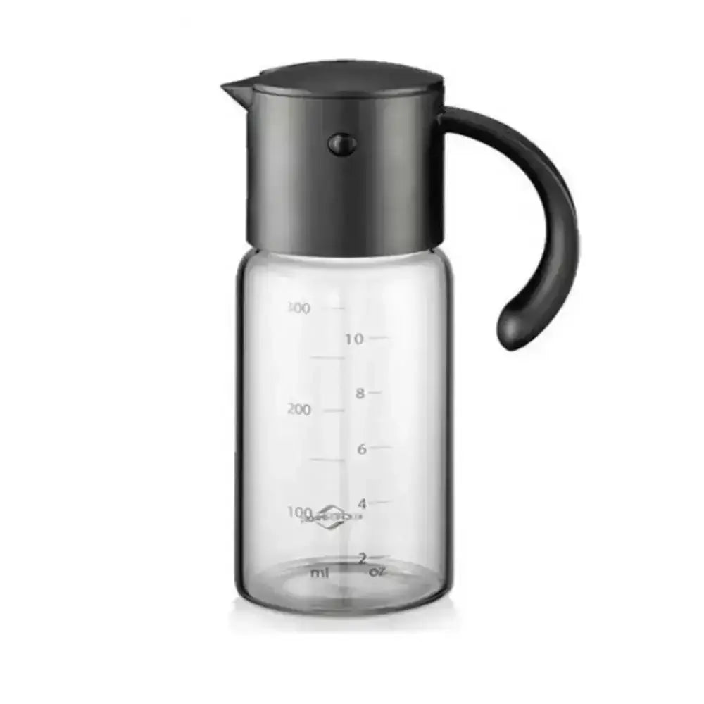 Clear glass oil and vinegar dispenser with black lid and handle on a white background