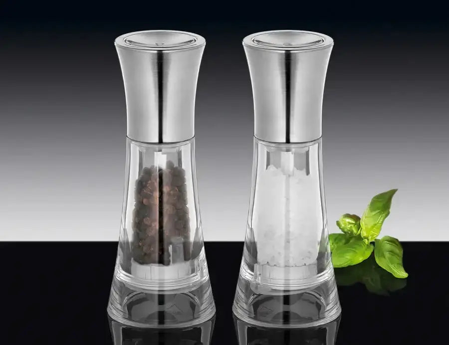 Two silver salt and pepper shakers with clear glass bodies on a reflective surface.