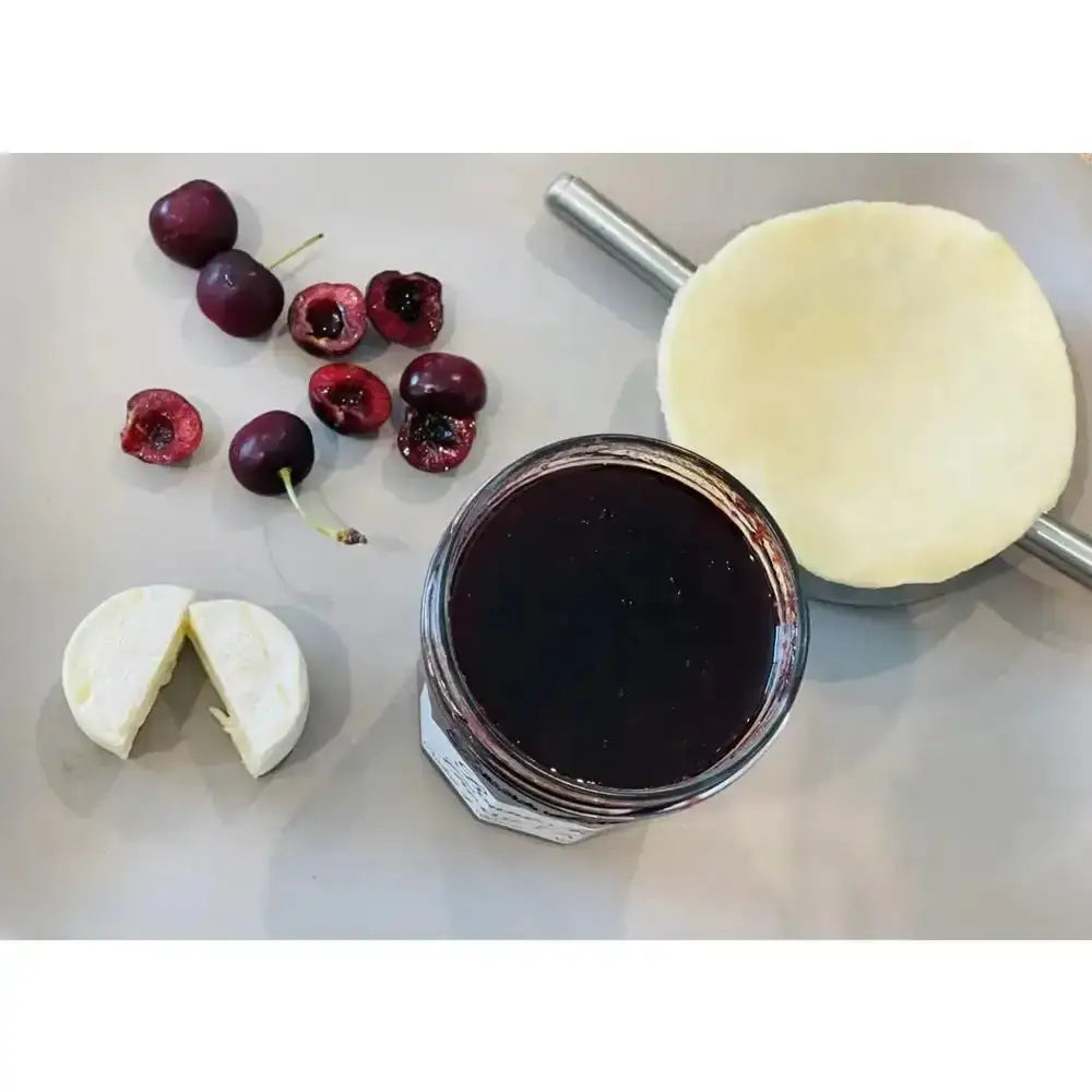 Jar of cherry pie filling with cherries and pie crust on a white surface