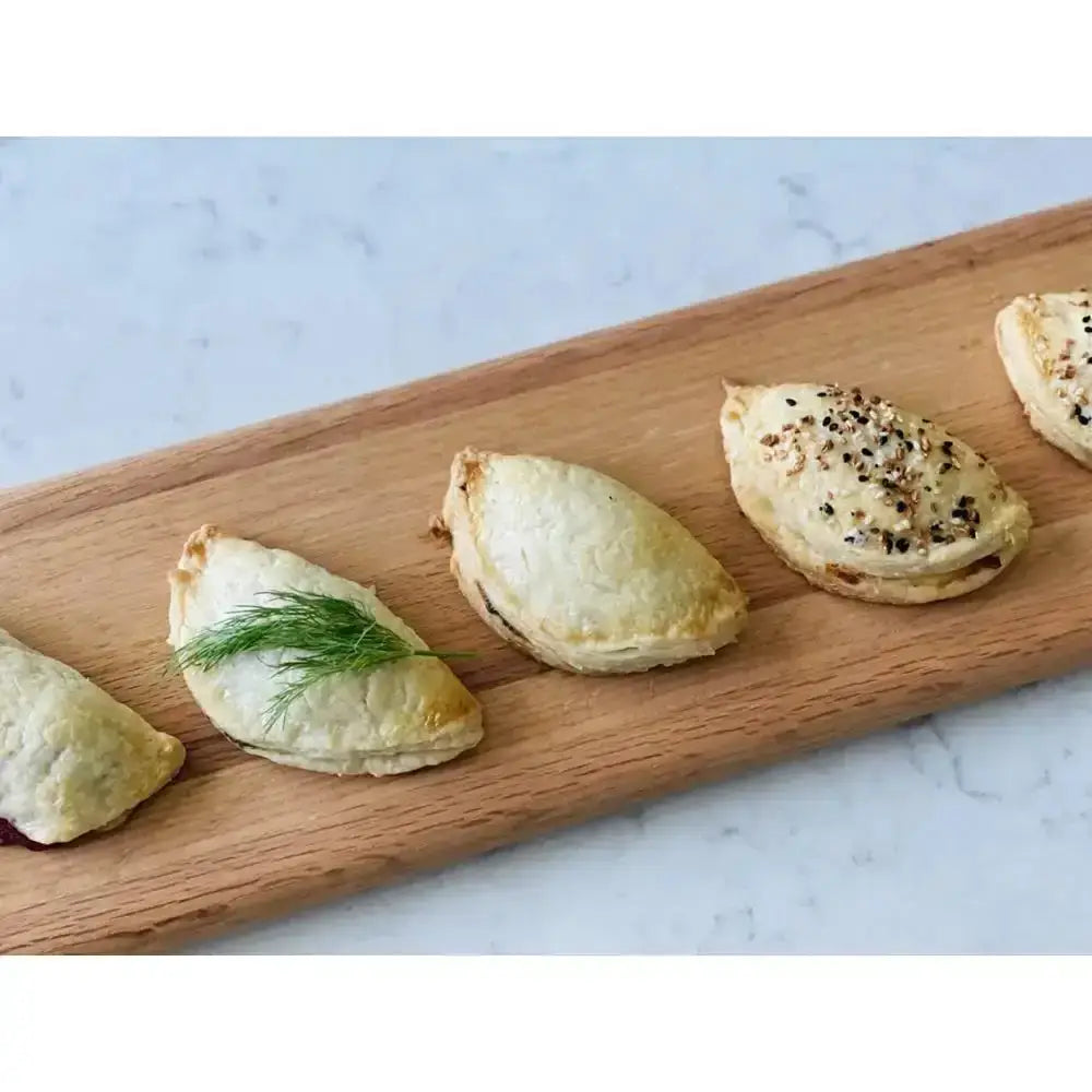 Small baked ravioli on a wooden board with a marble background