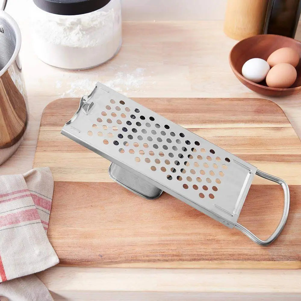 Metal box grater on a wooden cutting board with kitchen items in the background