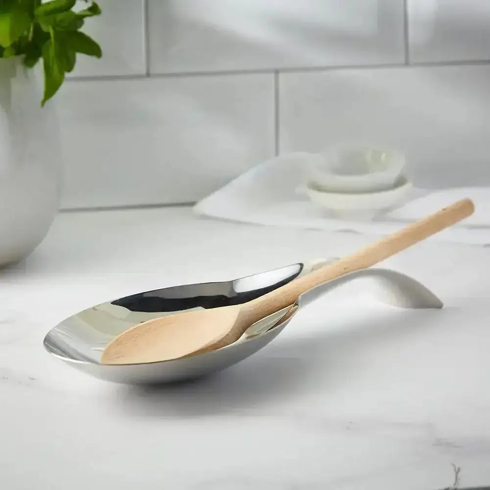 Serving spoon with wooden handle on a spoon rest and white surface