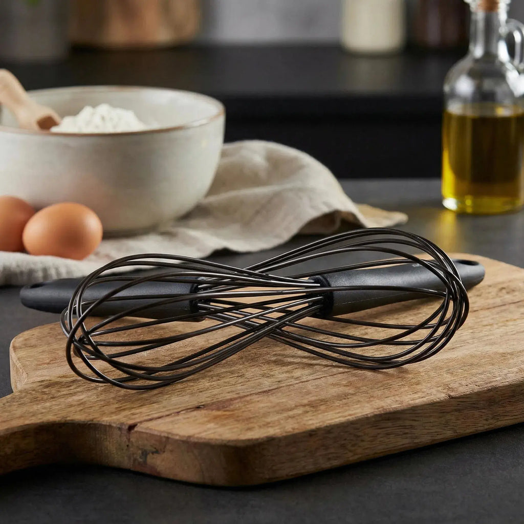 Küchenprofi trend silicone whisk 25cm with black wire and matte black handle resting on wooden cutting board