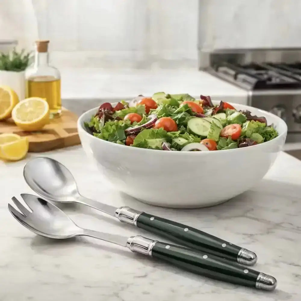 Bowl of salad with green-handled silverware on a kitchen counter